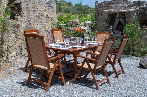 a wooden table with four chairs and glasses on it at Yiayia's Place in Vathiakón