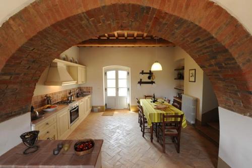 a kitchen with a table and a brick archway at Piccolo Borgo Gagnoni in Sinalunga