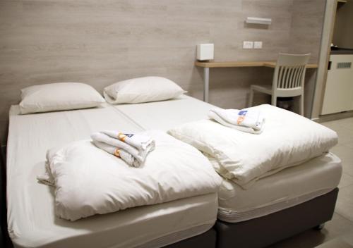 two beds in a room with white sheets and pillows at HI Rabin - Jerusalem Hostel in Jerusalem