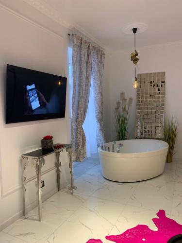 a bathroom with a tub and a tv on a wall at Tiltų 5 Jacuzzi Apartment in Klaipėda