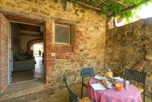 a table and chairs in a room with a brick wall at Piccolo Borgo Gagnoni in Sinalunga