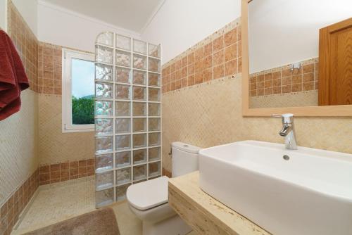 y baño con lavabo, aseo y espejo. en Villa Marina Malagarba By SunVillas Mallorca en Pollença