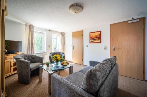 a living room with a couch and chairs and a tv at Murphy's Zimmer und Apartments in Bad Suderode