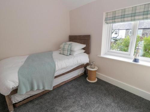 ein kleines Schlafzimmer mit einem Bett und einem Fenster in der Unterkunft Clock cottage in Conwy
