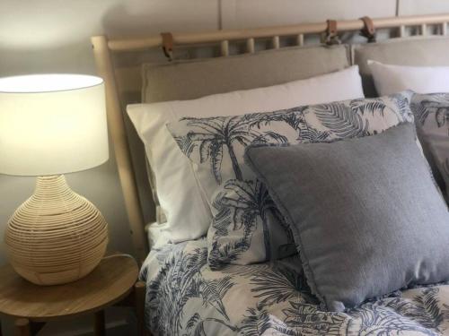 Una cama con una almohada y una lámpara sobre una mesa. en Cowra Cottage, en Cowra
