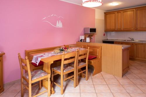eine Küche mit einem Tisch und Stühlen sowie einer lila Wand in der Unterkunft Baita Ruscello in Livigno