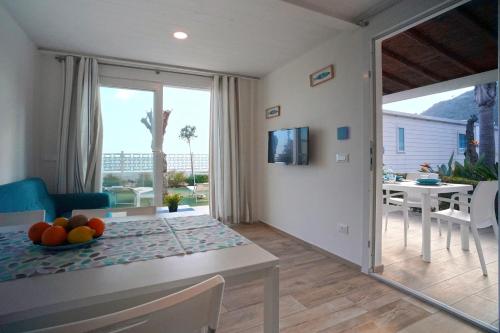 a dining room and living room with a table with fruit on it at Le Palme Village in Terracina