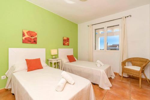 two beds in a room with green walls and a window at Villa Casa Nova in Sant Lluis