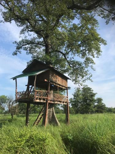 a tree house sitting in the middle of a field at Bardia Riverside View Park Resort - FR and EN speaking in Bhurkīā