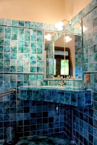 La salle de bains est pourvue de carrelage bleu, d'un lavabo et d'un miroir. dans l'établissement Maison charmante à Saint-Cybranet avec piscine partagée, à Saint-Cybranet