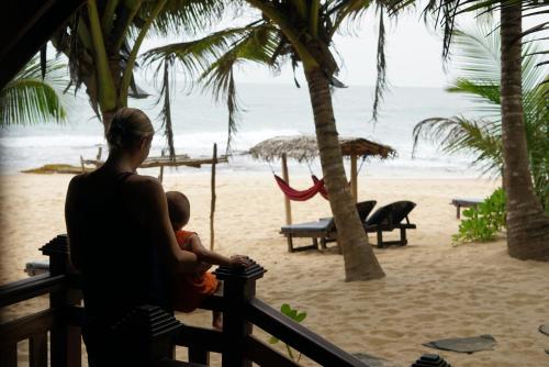 a man holding a baby looking at the beach at Ganesh Garden Beach Cabanas in Tangalle