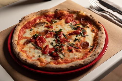 a pizza in a red plate on a table at Le Palme Village in Terracina