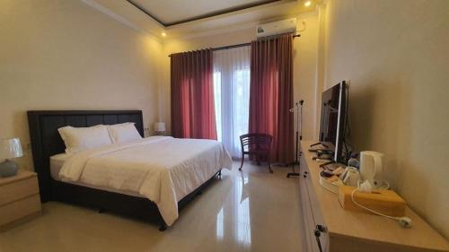 a bedroom with a bed and a television in it at Grand Puri Hotel in Nusa Penida