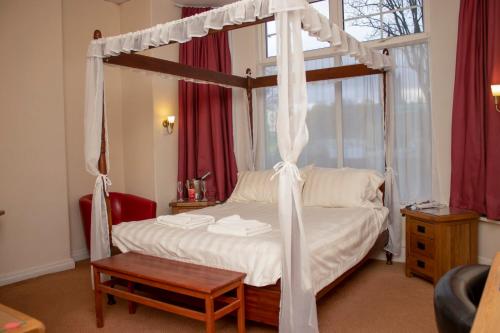 Ascot Grange Hotel - Voujon Resturant في ليدز: غرفة نوم مع سرير المظلة وطاولة