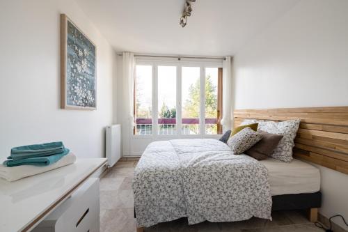 a white bedroom with a bed and a window at L'Impressionniste in Pontoise