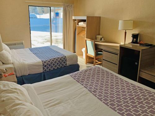 um quarto de hotel com duas camas e uma secretária em Econo Lodge Airport Quebec em Cidade de Quebec