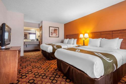a hotel room with two beds and a flat screen tv at Quality Inn & Suites Owasso US-169 in Owasso