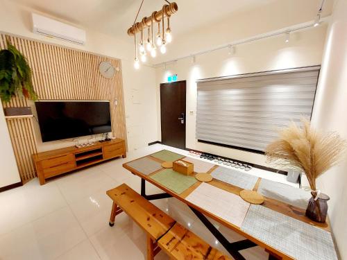 uma sala de estar com uma mesa e uma televisão de ecrã plano em 挈客茵民宿 em Zhushan