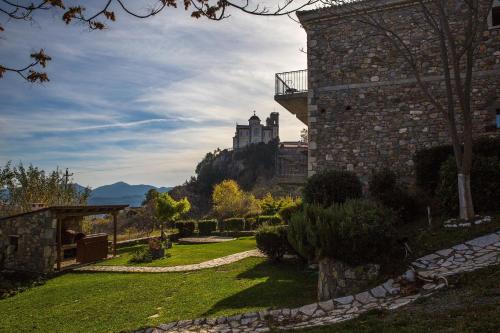 a garden in front of a building with a castle in the background at Hotel Papanikola in Piána