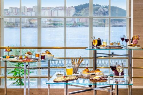 a table with food and drinks and a view of the water at Melia Maria Pita in A Coruña
