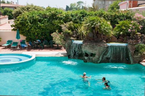 two people in a swimming pool with a waterfall at Le Residenze del Golfo di Orosei in Orosei