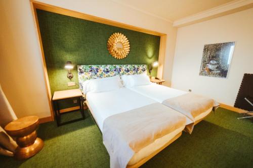 a bedroom with a large bed and a green wall at Barceló León Conde Luna in León