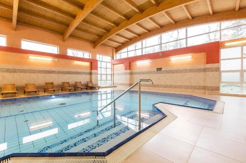 a pool in a building with a indoor swimming pool at Hotel Kudowa Manufaktura Relaksu in Kudowa-Zdrój