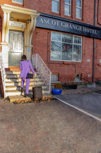 a girl walking up the stairs with a suitcase at Ascot Grange Hotel - Voujon Resturant in Leeds
