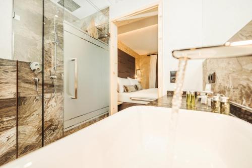 a bathroom with a shower and a tub in a room at Hotel Bergkristall Zillertal - Adults Only in Hippach
