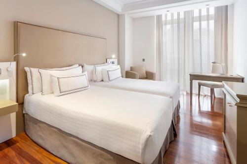 una habitación de hotel con una gran cama blanca y una mesa en Melia Maria Pita, en A Coruña