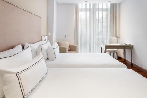 a white hotel room with a large white bed at Melia Maria Pita in A Coruña