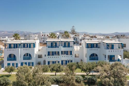 a large white apartment building with blue windows at Alykes Studios & Suites in Agios Prokopios