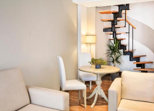 a living room with a table and a spiral staircase at Melia Maria Pita in A Coruña