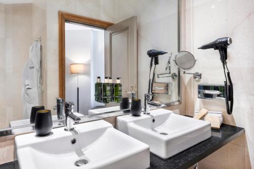 a bathroom with two white sinks and a mirror at Melia Maria Pita in A Coruña