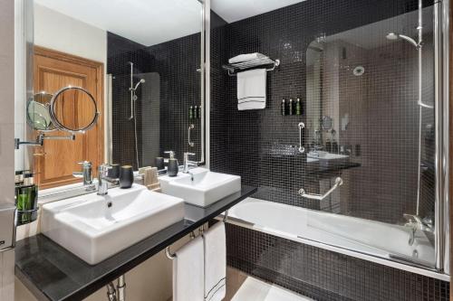 a bathroom with two sinks and a shower and a tub at Melia Maria Pita in A Coruña