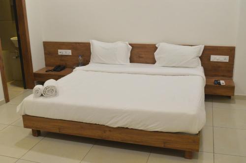 a bedroom with a large bed with white sheets and pillows at Hotel Revive in Veraval