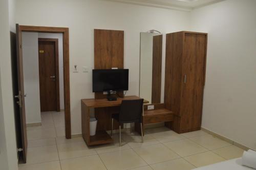 a room with a desk with a computer and a television at Hotel Revive in Veraval
