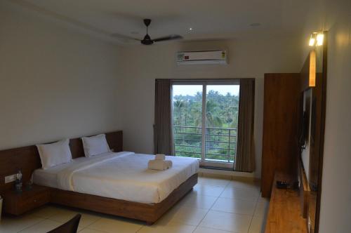 a bedroom with a bed and a large window at Hotel Revive in Veraval