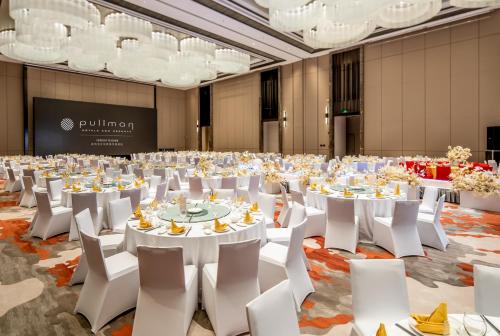 a large banquet hall with white tables and white chairs at Pullman Suzhou Taicang in Taicang