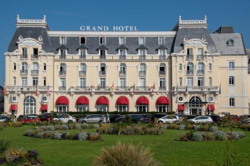 un grand bâtiment avec des voitures garées devant dans l'établissement #Bel appartement cosy Clos Mathilde !, à Cabourg