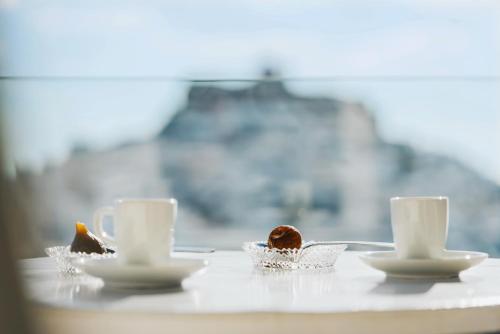 阿斯提帕莱亚镇安德罗梅塔度假酒店的桌子上放两个杯子和碟子