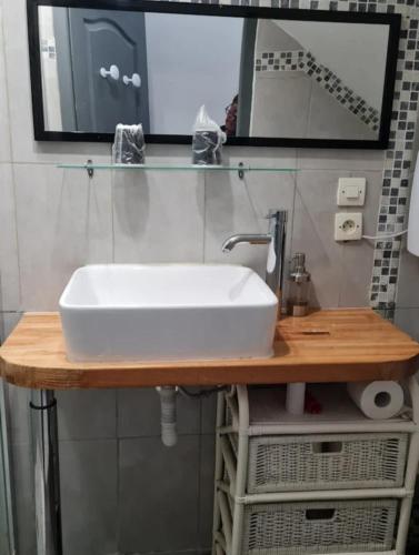 un lavabo blanc sur un comptoir en bois dans une salle de bain dans l'établissement Chambres d'hôtes des Oliviers, à Coaraze
