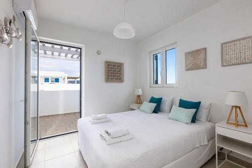 a white bedroom with a bed and a balcony at Triton Sea View Villa in Georgioupolis