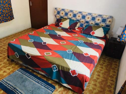 a bed with a colorful comforter and pillows on it at Feel At Home & be close to the Labadi Beach (5min) in Accra