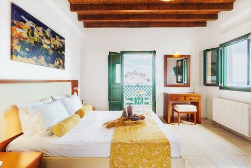 a bedroom with a bed and a desk and windows at Andromeda Resort in Astypalaia Town