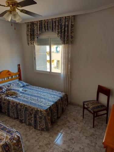 a bedroom with a bed and a chair and a window at Fuensanta 400m to Beach Med Syndicate 10 in Torrevieja