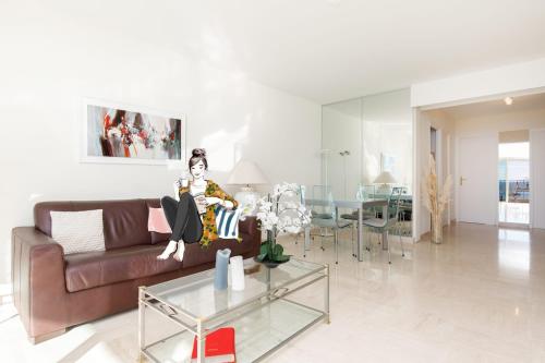 une femme assise sur un canapé dans un salon dans l'établissement On la Croisette fabulous sea view 1 bed, à Cannes