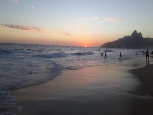 a group of people walking on the beach at sunset at Copacabana Apartment in Rio de Janeiro