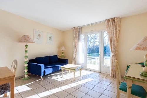 ein Wohnzimmer mit einem blauen Sofa und einem Tisch in der Unterkunft Residhotel Golf Grand Avignon in Vedène