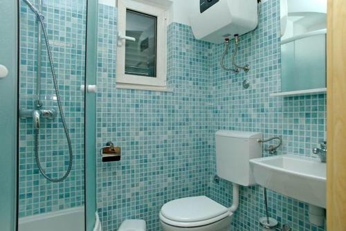 La salle de bains est pourvue de carrelage bleu, de toilettes et d'une douche. dans l'établissement Holiday house in Tri Porte Potirna with sea view, terrace, air conditioning, WiFi 39-1, à Potirna